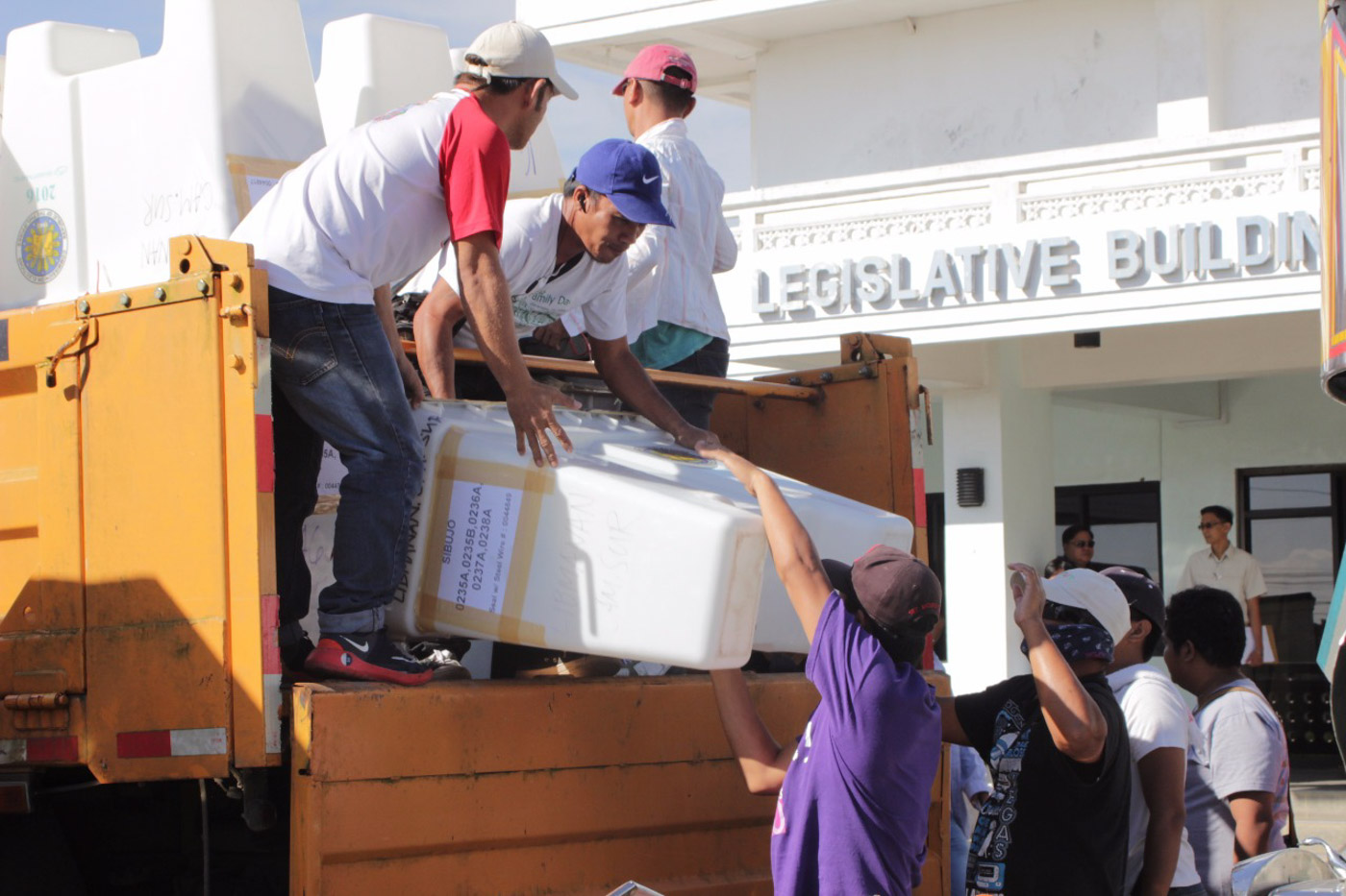 BALLOT RETRIEVAL. Men transfer ballot boxes from a truck to the Legislative Building in Pili, where representatives from the SC are waiting for them. All photos by OVP 