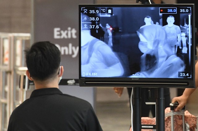 MORE CASES A woman, wearing a protective face mask amid fears about the spread of the new coronavirus COVID-19, is seen on a monitor as she passes a temperature screening check at Jewel Changi Airport in Singapore on February 27, 2020. File photo of Roslan Rahman / AFP  