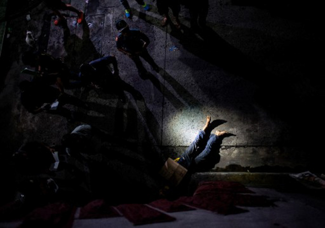 EDITORS NOTE: Graphic content / In this picture taken on July 8, 2016, police officers investigate the dead body of an alleged drug dealer, his face covered with packing tape and a placard reading "I'm a pusher", on a street in Manila. File photo by Noel Celis/AFP 