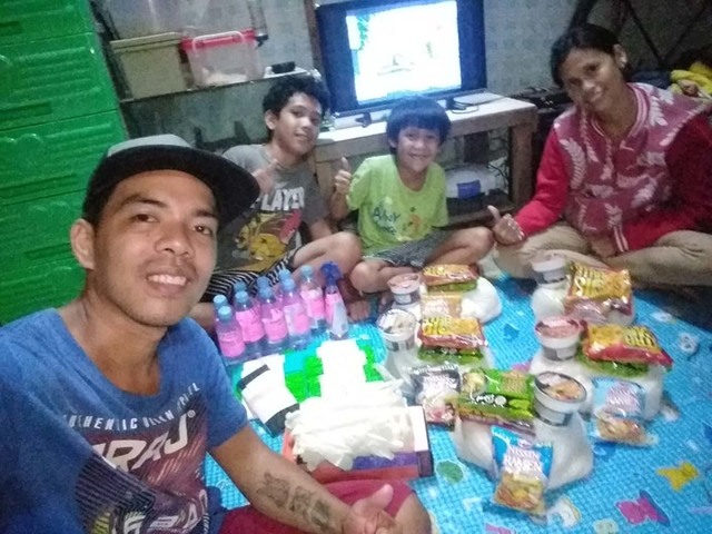 DONATIONS. Flores and his family pose with some of the food and cleaning supplies donated to them by some netizens. Photo courtesy of Flores  