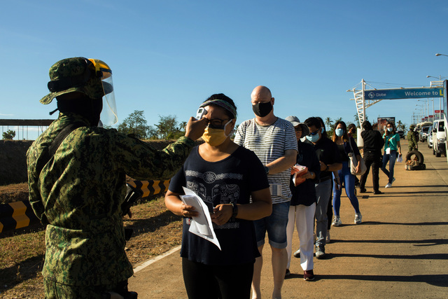 BATTLE VS COVID-19. A police officer uses a thermal scanner to check a Filipina's body temperature upon entering Laguindingan Airport in Laguindingan, Misamis Oriental. Region 10 Tourism Department Photo 