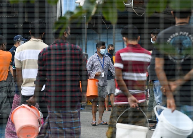 THE MIGRANT WORKERS. Residents queue to get their food in Tuas South's foreign worker dormitory that has been placed under government restriction as a preventive measure against the spread of the COVID-19 coronavirus in Singapore on April 19, 2020. Photo by Roslan Rahman / AFP 