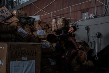 RELIEF GOODS. A volunteer carries relief goods for a waiting vehicle inside the deck of the BRP Davao del Sur. Photo by Bobby Lagsa/Rappler 