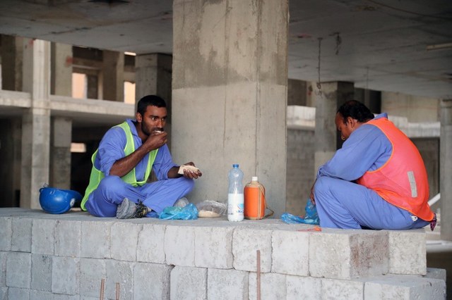 NEW POLICY. Migrant workers eat during a break at a construction site in the Qatari capital Doha on December 6, 2016. Photo by AFP 