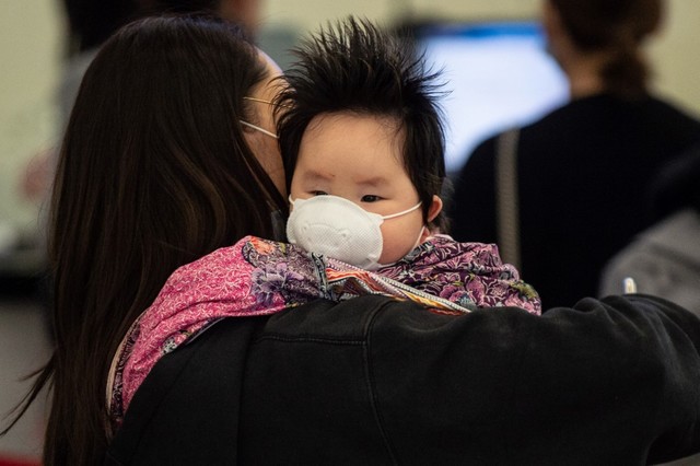 Seorang perempuan bersama anak di Hongkong mengenakan masker wajah untuk pencegahan