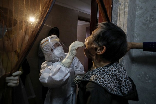 TESTS. A medical worker takes a swab sample from an elderly resident who is unable to conveniently go out for a COVID-19 test at his home in Wuhan, central China's Hubei Province, on May 14, 2020. Photo by STR / AFP 