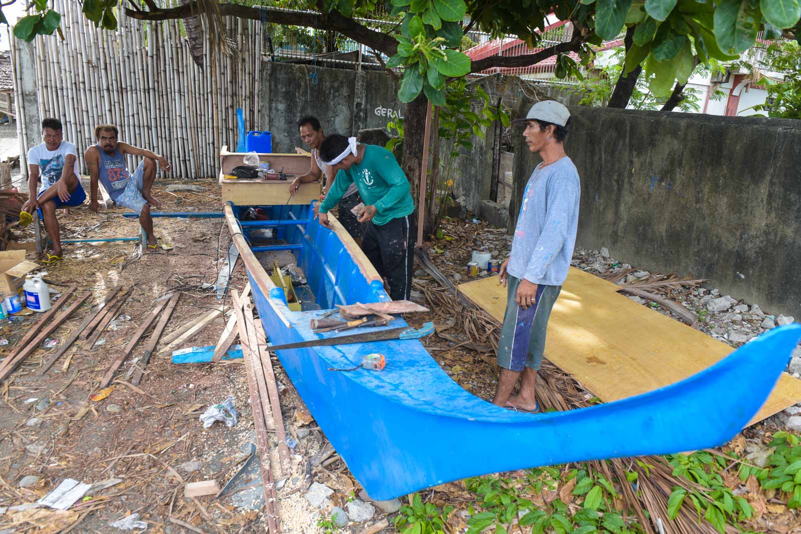 BACK TO WORK. Boy Gordiones (center) makes the necessary refurbishments to his fiberglass boat which he will pass on to his children in the future.