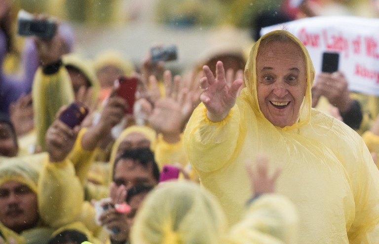 POPE IN A RAINCOAT. Pope Francis (R) wears a plastic poncho as he waves to well-wishers after a Mass in Tacloban City on January 17, 2015. Photo by Johannes Eisele/AFP  