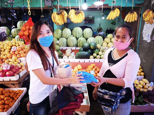 MAKESHIFT MASKS. A volunteer distributes makeshift masks made by the group for the vendors in Baybay City Market. Photo from Tabang PH